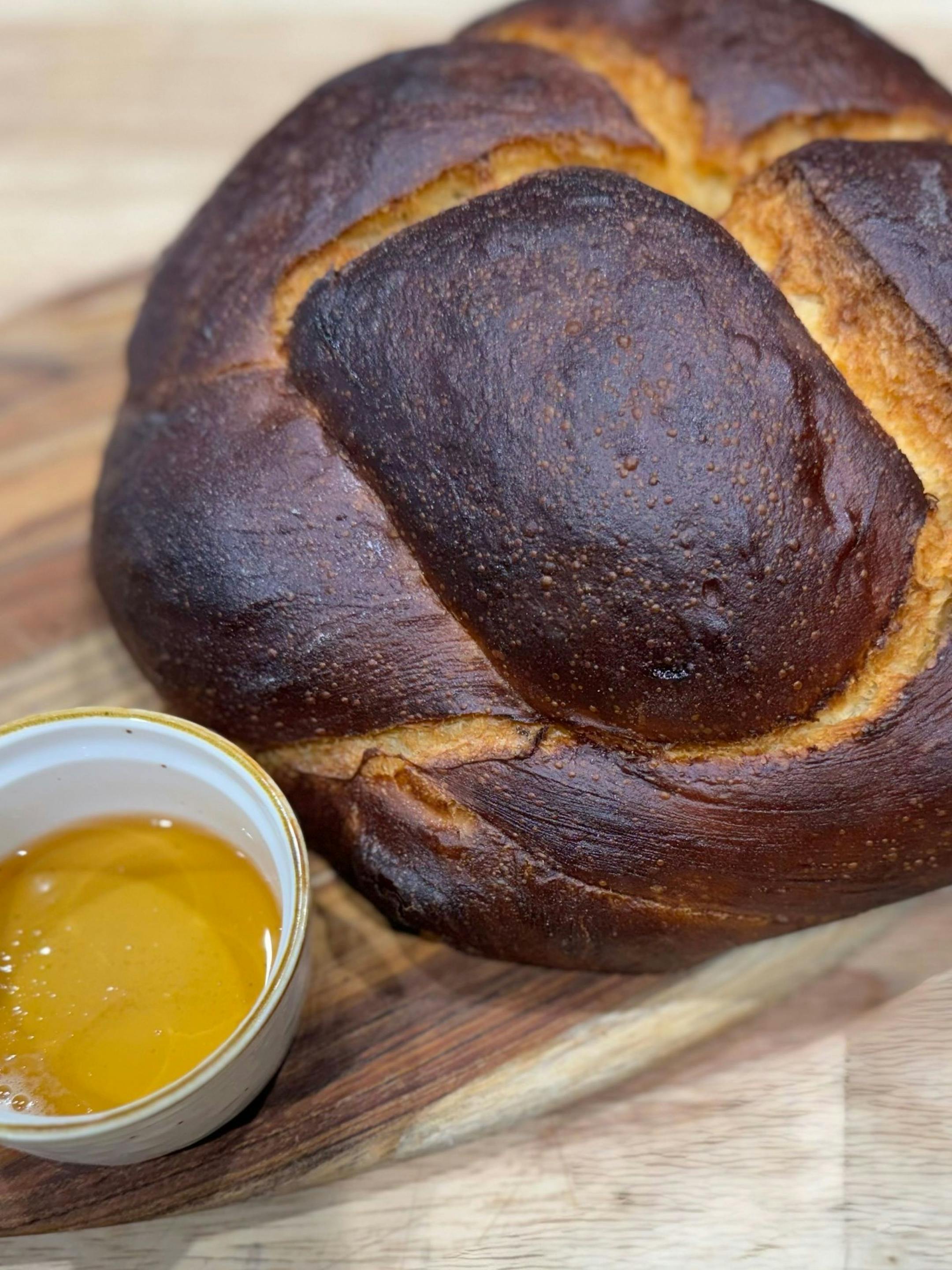 A round loaf of challah with a bowl of honey.