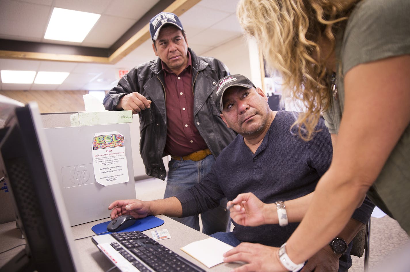 Jose Martinez, from left, and Ernesto Valle of Las Vegas, Nevada get help from June Hesser, a customer service representative at Job Service North Dakota in Williston, North Dakota on Tuesday, March 31, 2015. Martinez and Valle are seasonal construction workers who work in Las Vegas in the winter and come to Williston for work in the summer. ] LEILA NAVIDI leila.navidi@startribune.com /