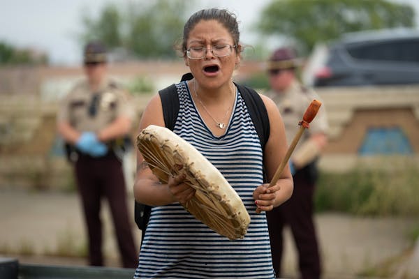 Khaloni Freemont sings while State Troopers move people out of an encampment. Nearly one week after MnDOT posted trespass notices at the Wall of Forgo