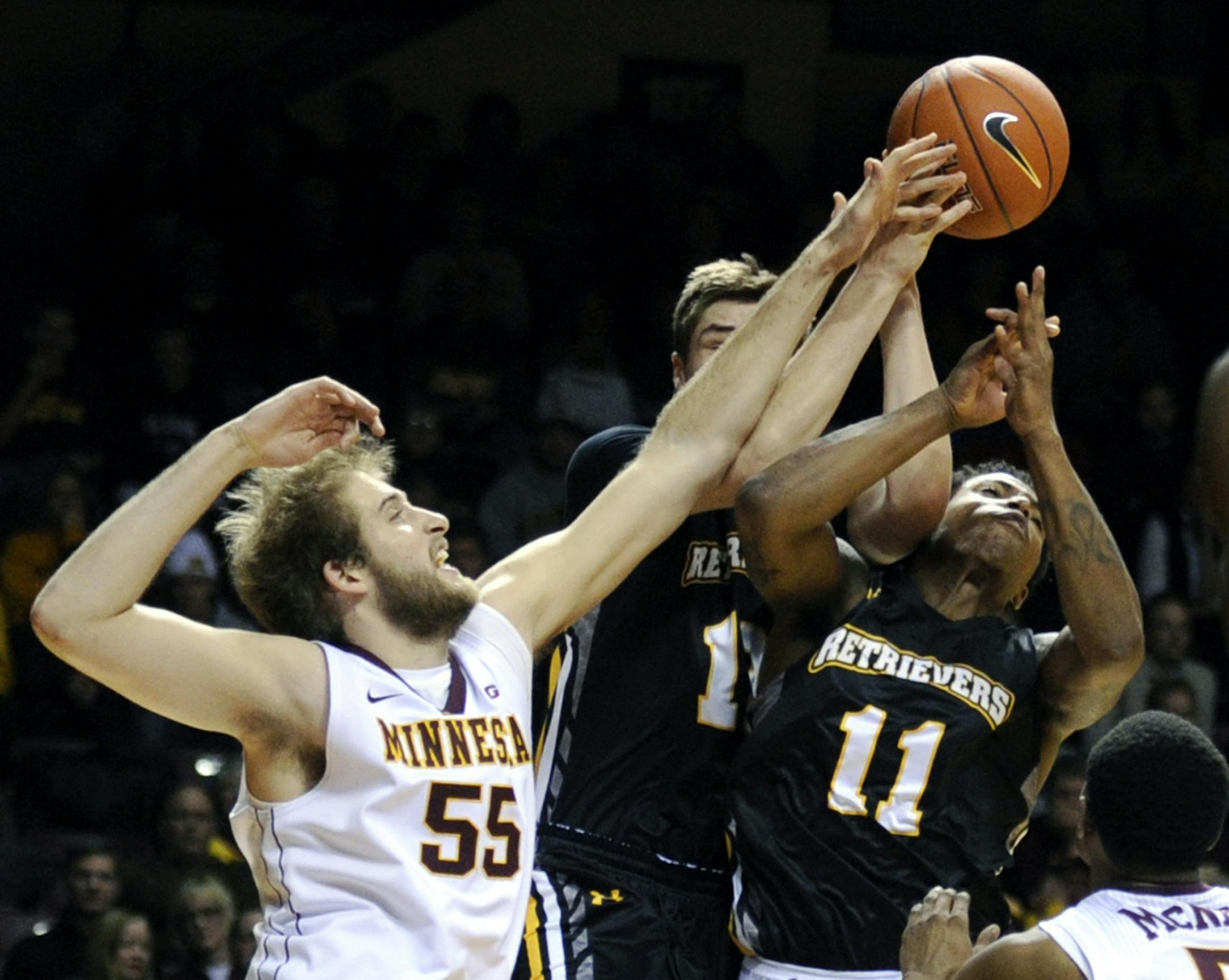 Maryland-Baltimore County guard Will Darley, center, and guard Charles Taylor (11) reach for a rebound with Minnesota center Elliott Eliason (55) during the first half of an NCAA college basketball game Saturday, Nov. 22, 2014, in Minneapolis.