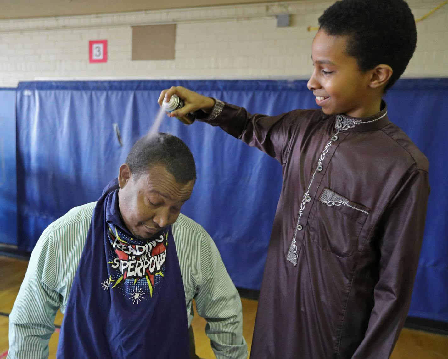 STEP Academy fifth grader Hussein Mohammed sprayed hair dye on Mustafa Ibrahim, the school's director, as part of the celebration for the students meeting their reading goals for the month of March