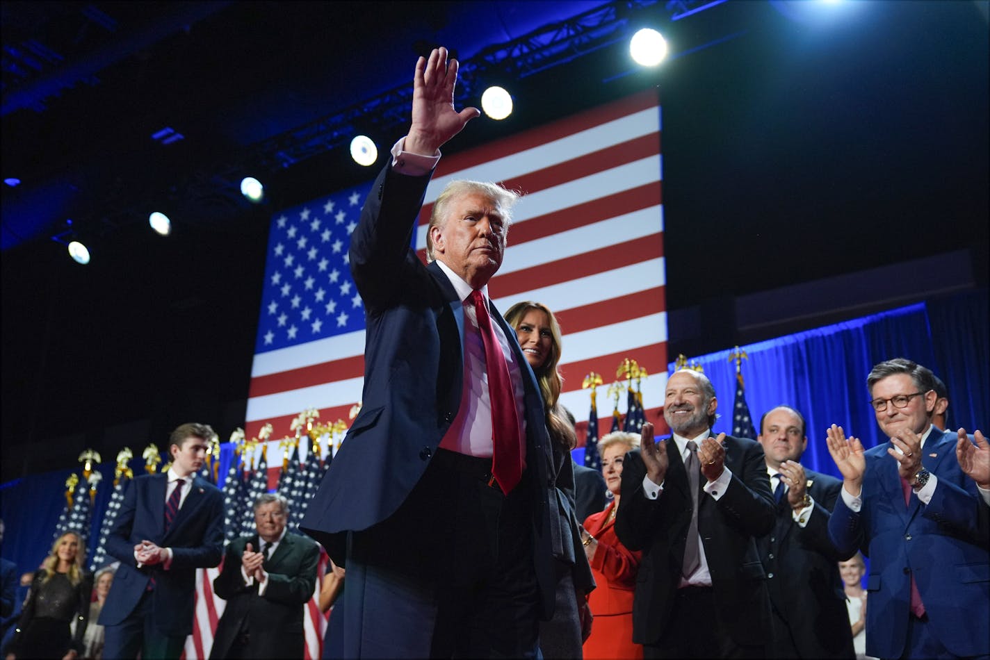 Republican presidential nominee former President Donald Trump waves as he walks with former first lady Melania Trump at an election night watch party at the Palm Beach Convention Center early Wednesday.