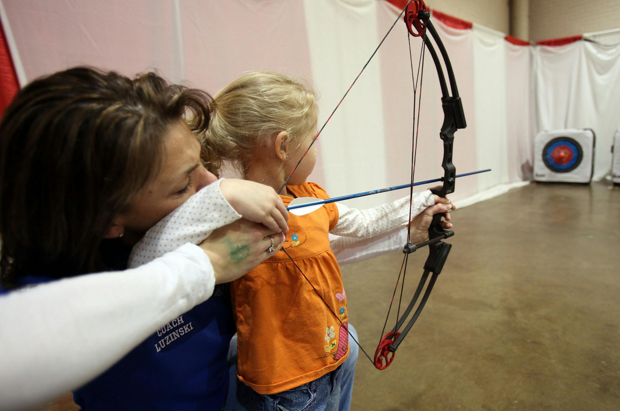 KYNDELL HARKNESS ‚Ä¢ kyndell.harkness@startribune.com ST. PAUL 01/14/11 The 2011 Minnesota Sportsmen's Show at the RiverCentre in St. Paul Jan 13th-16th IN THIS PHOTO : ] Alayna McInerny, 5, of St. Paul and archery instructor Deb Luzinski took aim at attarget in the Archery in the Schools section at the 2011 Minnesota Sportsmen's Show at the RiverCentre in St. Paul.