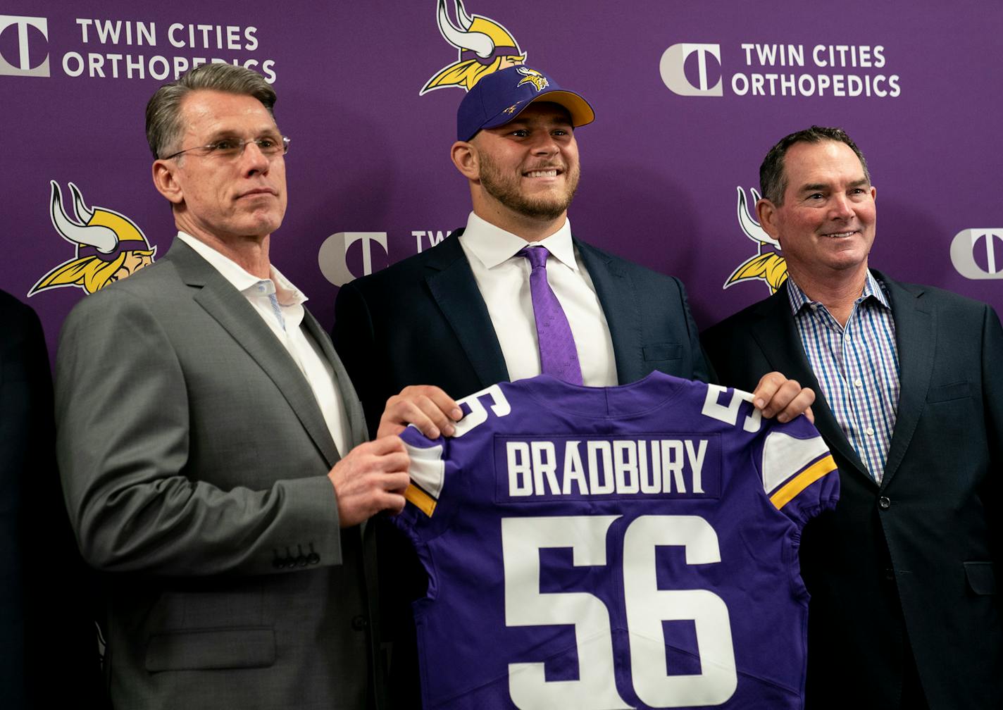 Minnesota Vikings first-round draft pick Garrett Bradbury holds his jersey with, from left, general manager Rick Spielman and head coach Mike Zimmer during a news conference at the TCO Performance Center News in Eagan, Minn., on Friday, April 26, 2019. (/TNS)