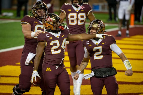 Tanner Morgan celebrates a Gophers touchdown with running back Mohamed Ibrahim during Saturday's loss to Michigan.