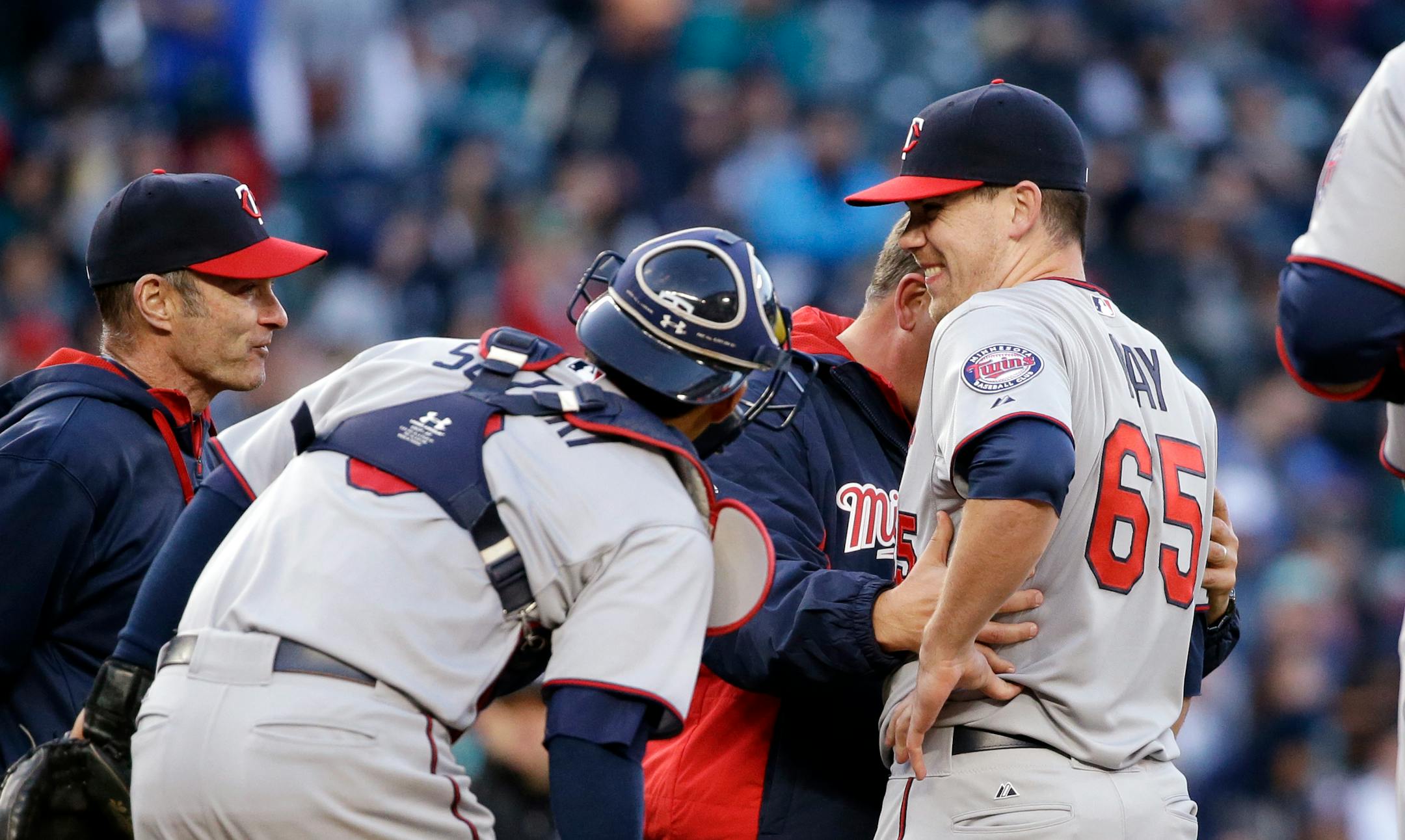 Minnesota Twins starting pitcher Trevor May (65) is checked after he was hit by a line drive from Seattle Mariners' Kyle Seager in the fourth inning of a baseball game Saturday, April 25, 2015, in Seattle. May left the game after completing the play for the out. (AP Photo/Elaine Thompson)