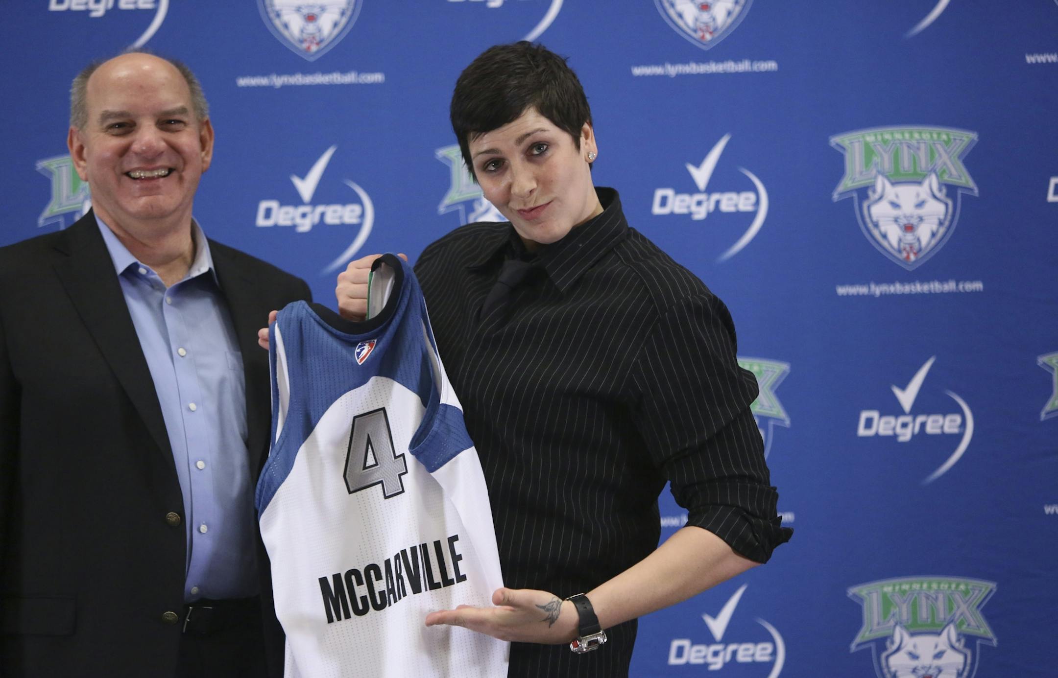 Executive Vice President Roger Griffith and former Gopher center Janel McCarville held up her new Lynx jersey as she underlines the name during a press conference at The Depot in Minneapolis on Friday.