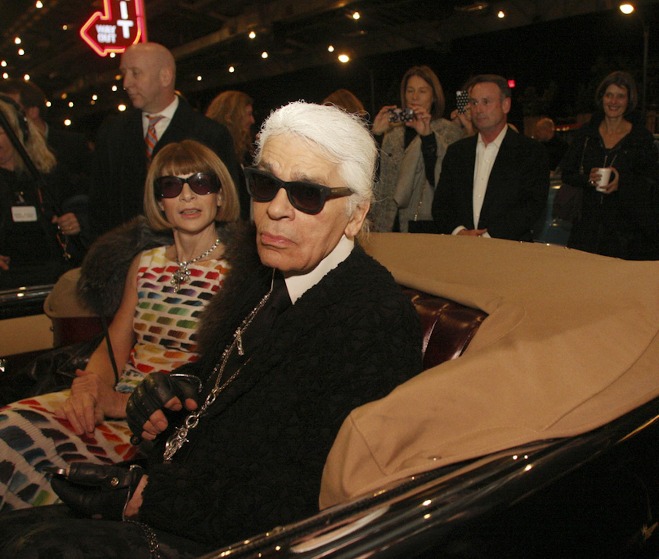 FILE-- Karl Lagerfeld and Vogue editor Anna Wintour sit in a classic car during the premier of his movie, "The Return," at Fair Park in Dallas, Dec. 10, 2013. Lagerfeld, the most prolific designer of the 20th and 21st centuries and a man whose career formed the prototype of the modern luxury fashion industry, died on Feb. 19, 2019, in Paris. He was 85. (Mark Graham/The New York Times)