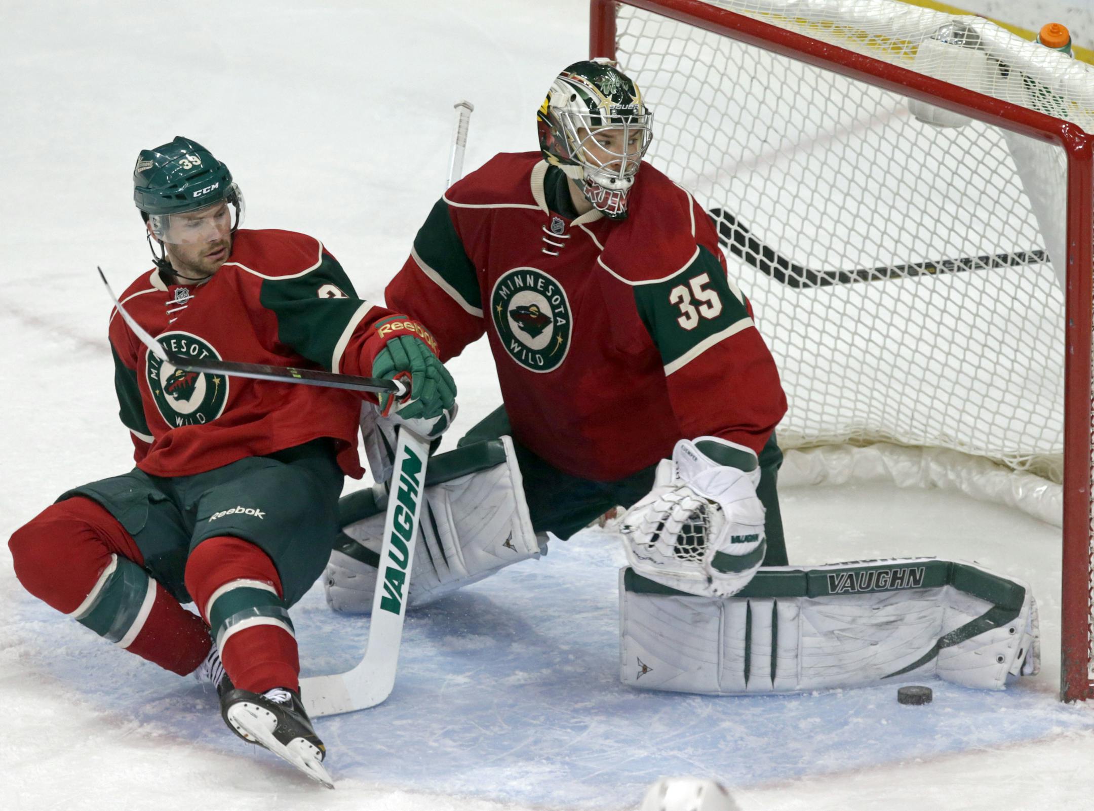 Minnesota Wild goalie Darcy Kuemper, right, stops a shot as Nate Prosser skates into him in the first period of an NHL hockey game against the Columbus Blue Jackets, Saturday, March 15, 2014, in St. Paul, Minn. (AP Photo/Jim Mone)