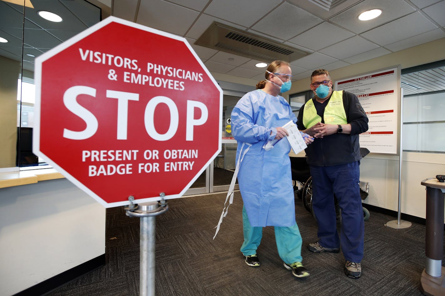 Medical personnel discuss patients that had been admitted for testing for the coronavirus at the entrance Central Maine Medical Center on Friday, March 13, 2020, in Lewiston, Maine. U.S. hospitals are setting up circus-like triage tents, calling doctors out of retirement, guarding their supplies of face masks and making plans to cancel elective surgery as they brace for an expected onslaught of coronavirus patients. (AP Photo/Robert F. Bukaty)