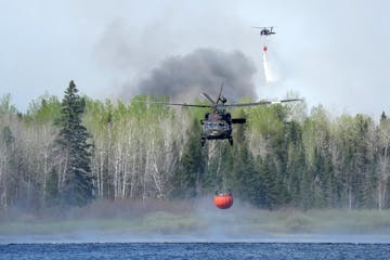 Crews from the Minnesota Army National Guard use Blackhawk helicopters to scoop water from Indian Lake as they worked to douse the Camp House fire on