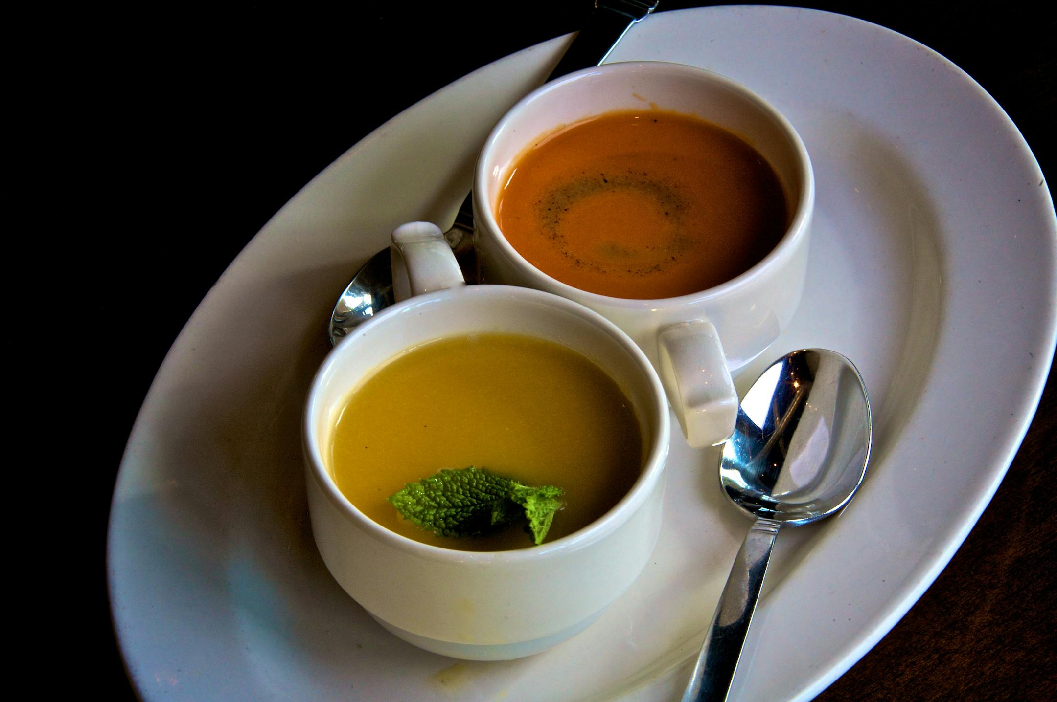Two chilled soups: Cantaloupe-peach soup garnished with fresh mint, and a roasted tomato gazpacho finished with roasted hazelnut oil.