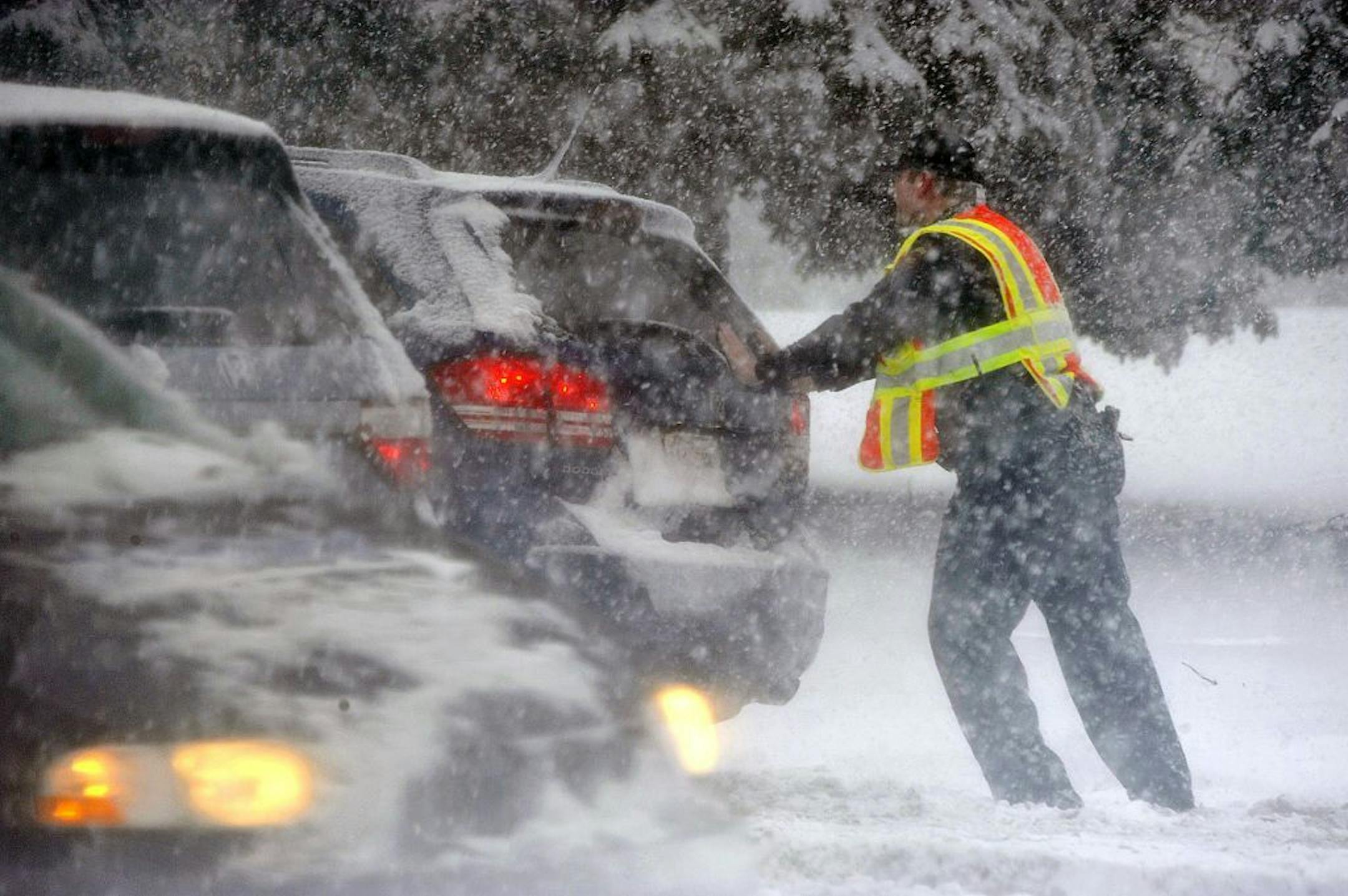 A Kenosha, Wis., police officer pushes a vehicle stuck in snow on a slick hill as a winter storm dropped more snow on southeastern Wisconsin, Tuesday, Feb. 26, 2013.
