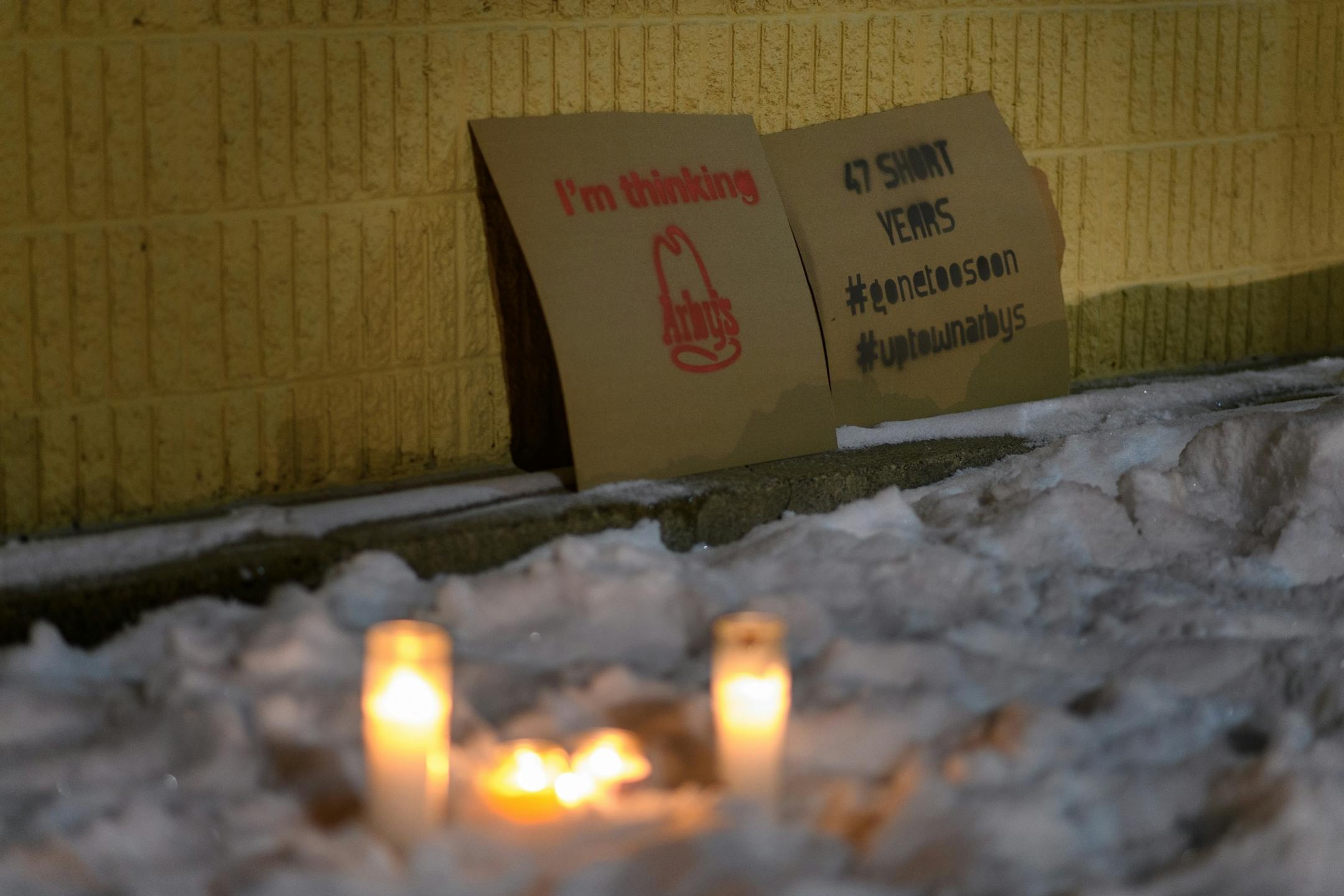 Candles were left in the snow in front of the now-closed Uptown Arby's Friday night.
