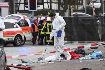 Police and rescue workers stand next to the scene of the accident with a car that is said to have crashed into a carnival parade in Volkmarsen, centra