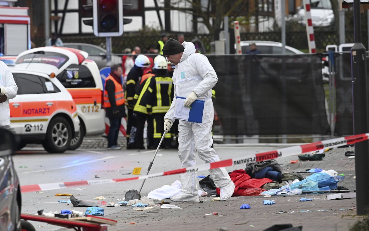 Police and rescue workers stand next to the scene of the accident with a car that is said to have crashed into a carnival parade in Volkmarsen, central Germany, Monday, Feb. 24, 2020. Several people have been injured, according to the police. The driver had been arrested by the police. (Uwe Zucchi/dpa via AP)