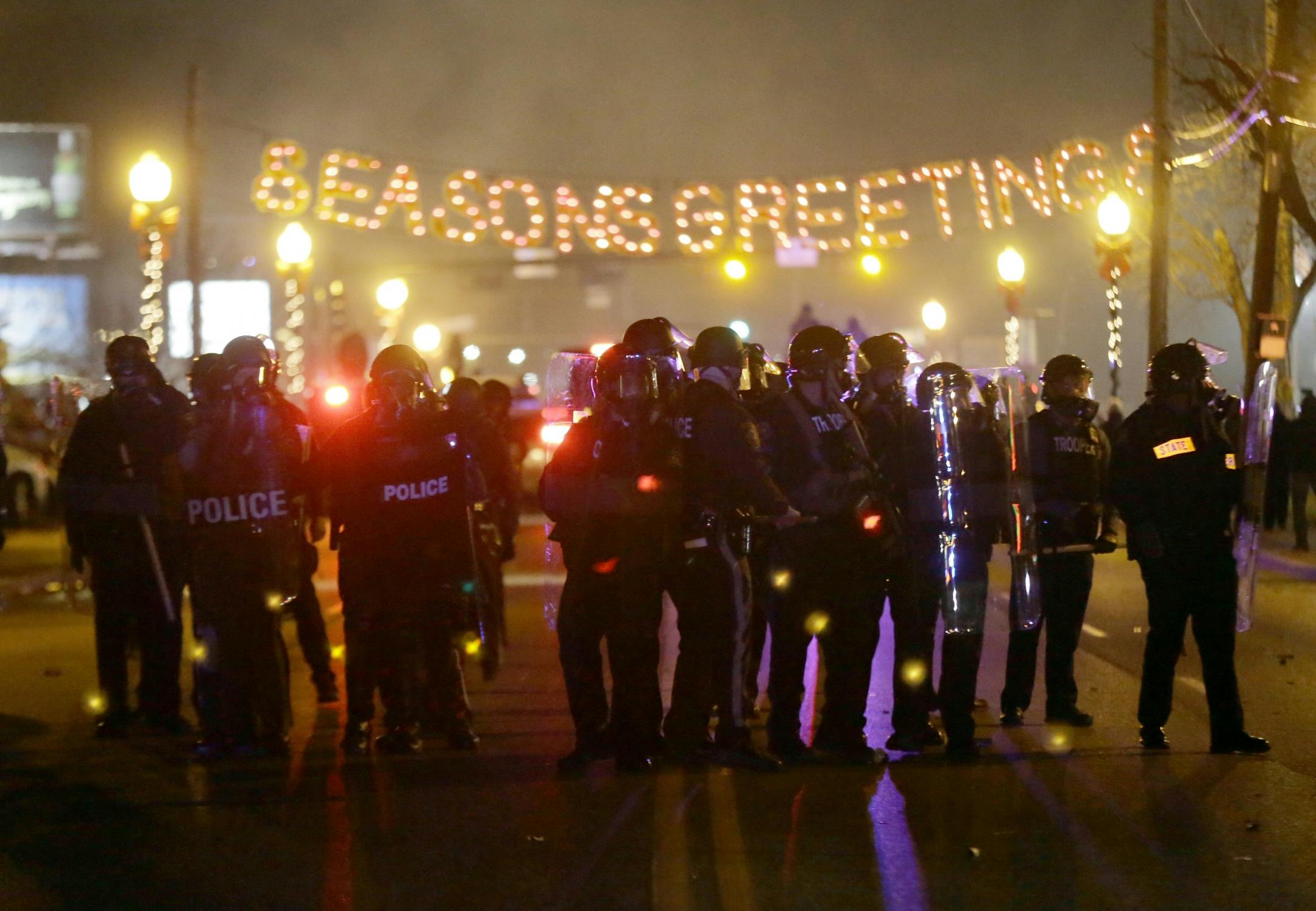 Police gather on the street as protesters react after the announcement of the grand jury decision Monday, Nov. 24, 2014, in Ferguson, Mo. A grand jury has decided not to indict Ferguson police officer Darren Wilson in the death of Michael Brown, the unarmed, black 18-year-old whose fatal shooting sparked sometimes violent protests.
