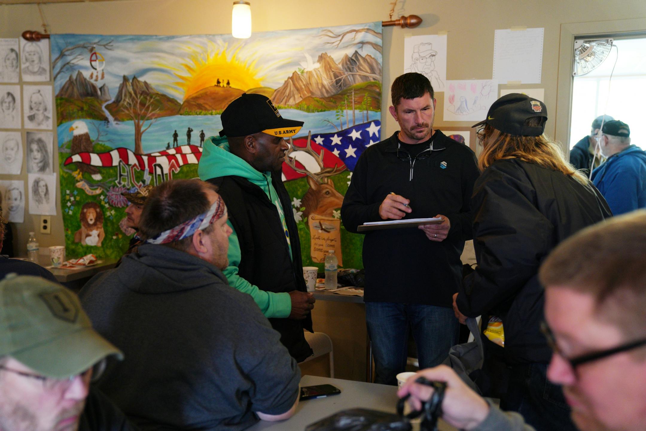 Tom McKenna, center, talked with a pair of veterans as he compiled a list for them to go shopping for free supplies at his attached donation center.