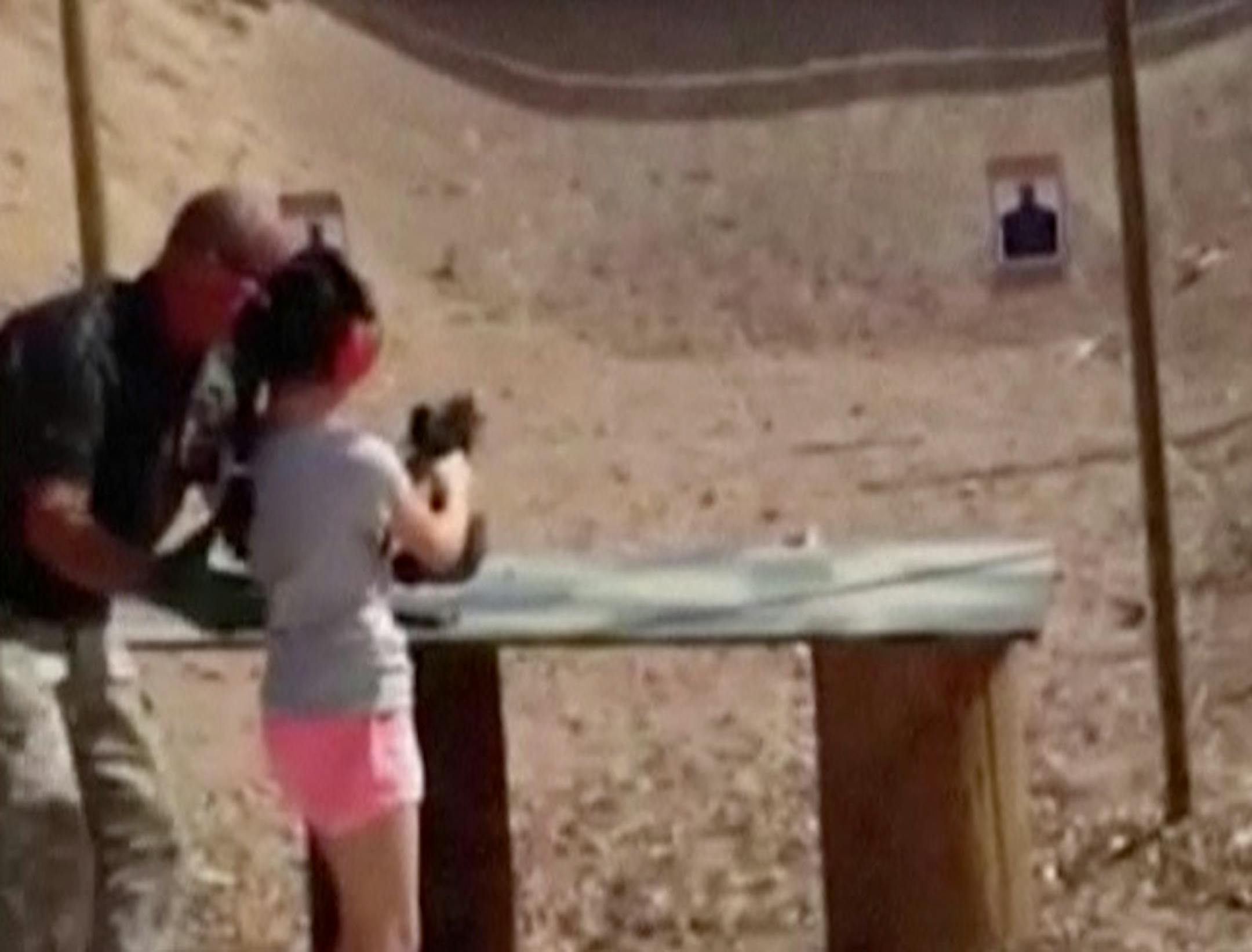 In this Aug. 25, 2014 image made from video provided by the Mohave County Sheriff Department, firing-range instructor Charles Vacca, left, shows a 9-year old girl how to use an Uzi.
