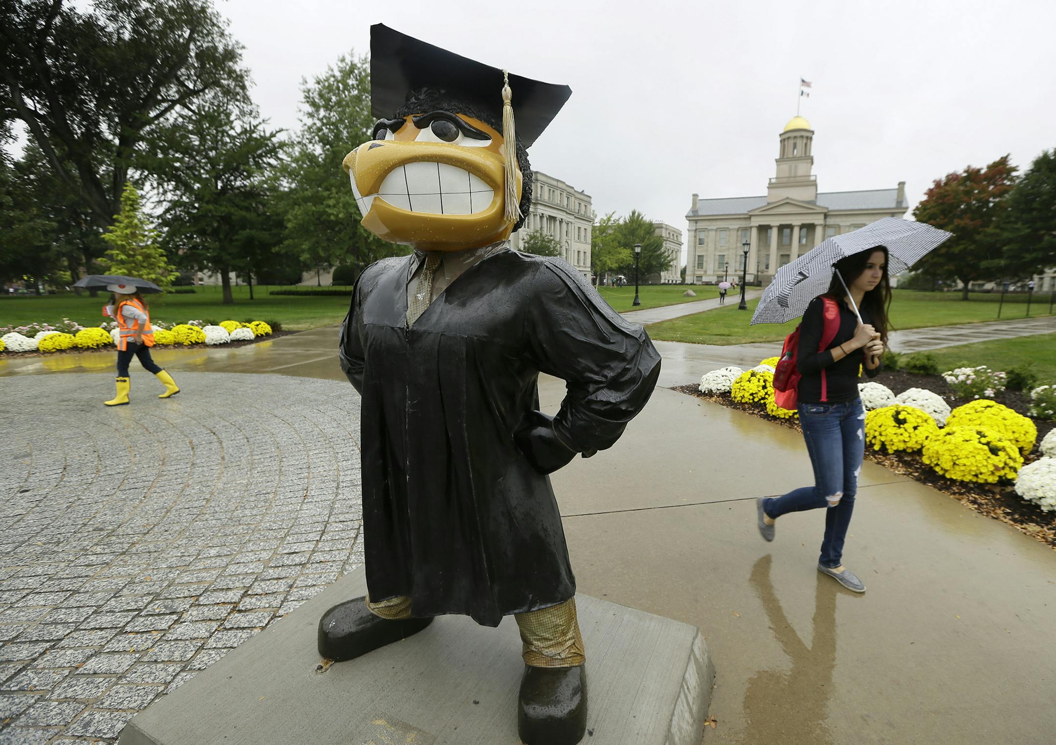 Students walk across campus at the University of Iowa, Thursday, Oct. 2, 2014, in Iowa City, Iowa. The Board of Regents will unveil plans Thursday to restructure how Iowa‚Äôs three public universities perform routine administrative functions, eliminating hundreds of jobs while saving tens of millions of dollars. (AP Photo/Charlie Neibergall) ORG XMIT: IACN104