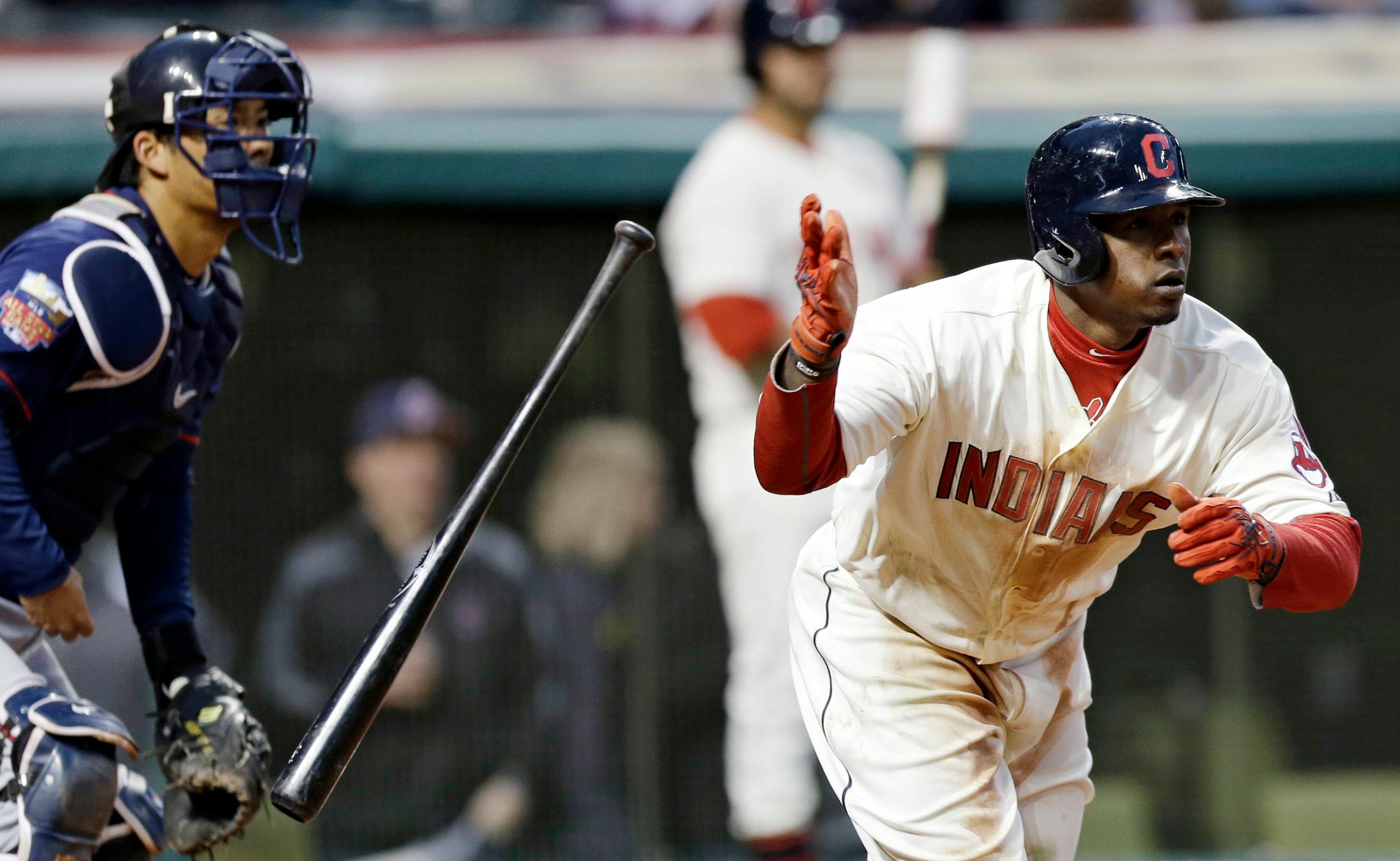 Cleveland Indians' Nyjer Morgan, right, throws his bat as he watches the ball after hitting an RBI-single off Minnesota Twins relief pitcher Casey Fien in the seventh inning of a baseball game on Friday, April 4, 2014, in Cleveland. Indians' Yan Gomes scored. Twins catcher Kurt Suzuki, left, also watches. (AP Photo/Tony Dejak)