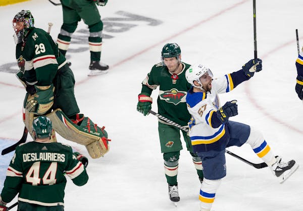 David Perron (57) of the St. Louis Blues celebrates in front of Minnesota Wild defenseman Dmitry Kulikovafter after getting the puck past Minnesota Wi