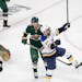 David Perron (57) of the St. Louis Blues celebrates in front of Minnesota Wild defenseman Dmitry Kulikovafter after getting the puck past Minnesota Wi