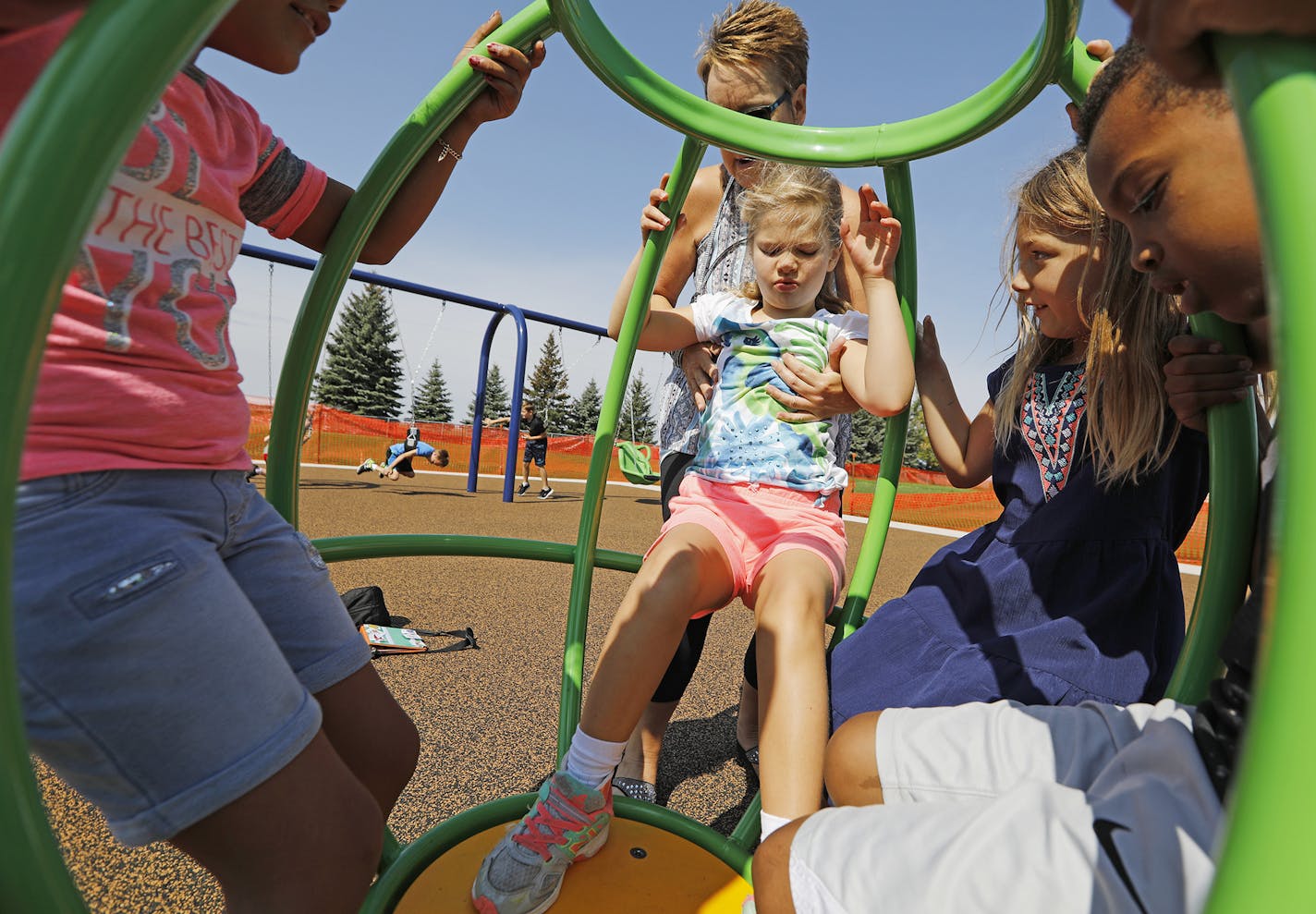 Fourth grader Emily Quandt, center, gets some help from special education paraprofessional Lorrie Shortridge getting into a spinning piece of playground equipment with other children. From left is Joselyn Vallejo Guatemala, Lilly Albricht and Ikran Abdi. ] LEILA NAVIDI &#xef; leila.navidi@startribune.com BACKGROUND INFORMATION: Recess of Lake Elmo Elementary School in Lake Elmo on Monday, September 17, 2018. Lake Elmo Elementary PTA raised nearly $100,000 for an accessible playground, which was