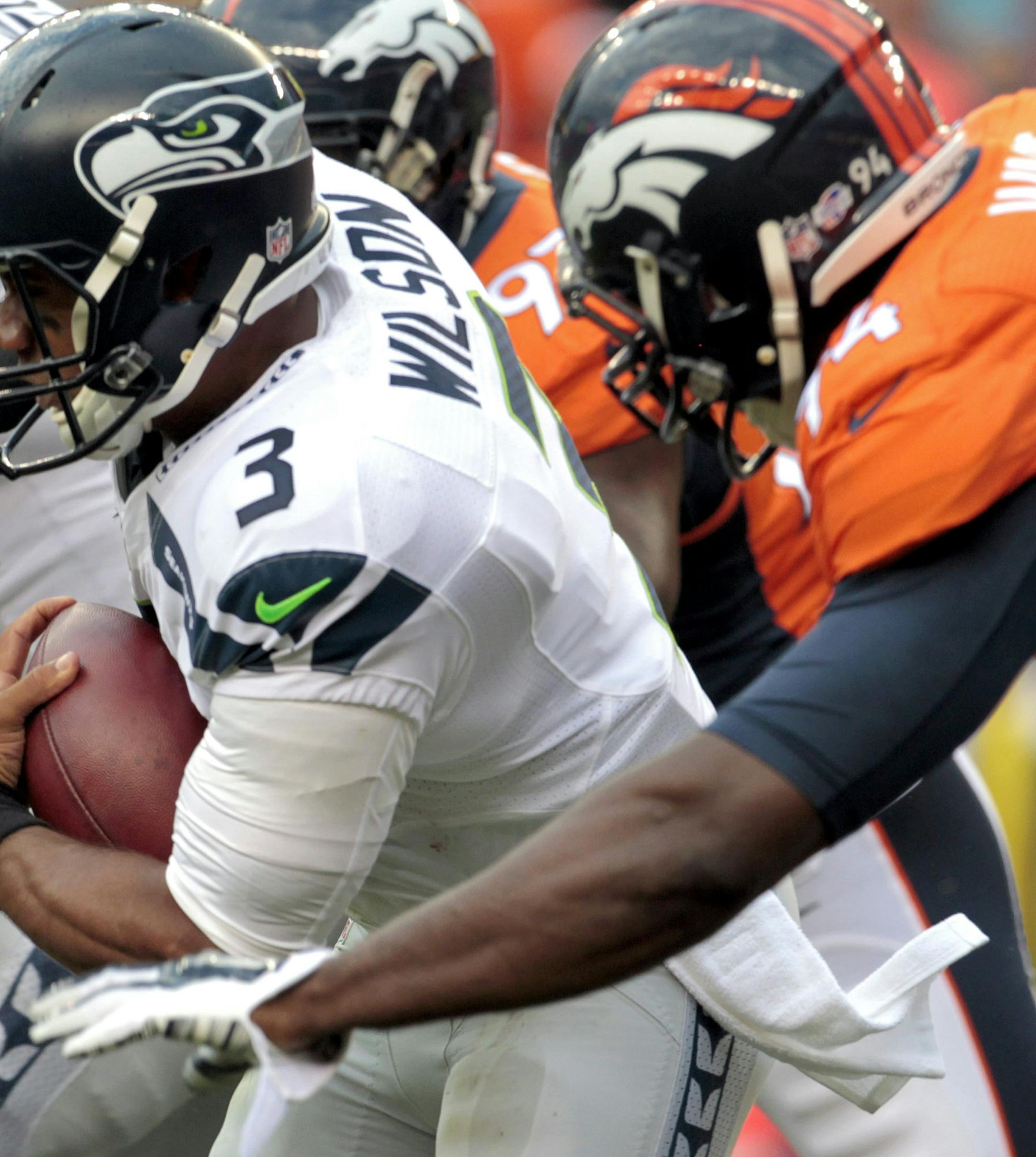 Seattle Seahawks quarterback Russell Wilson (3) is pursued by Denver Broncos defensive end DeMarcus Ware (94) during the first half of an NFL preseason football game, Thursday, Aug. 7, 2014, in Denver. (AP Photo/Joe Mahoney) ORG XMIT: COMY1