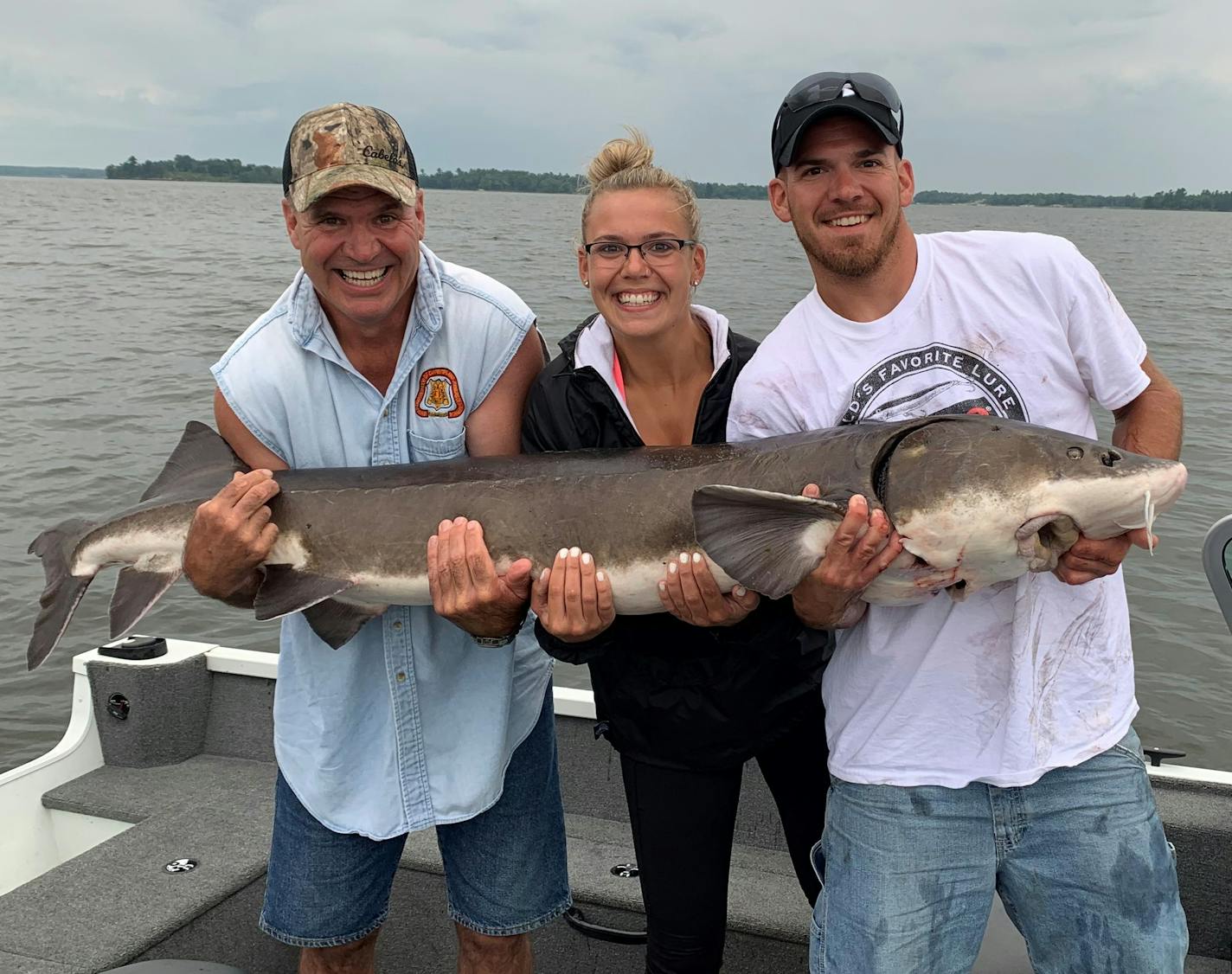 (From left) It took the combined arms of Paul Stay, Danielle Stay and Dustin Stay to hold up this 68-inch lake sturgeon from Lake Kabetogama.