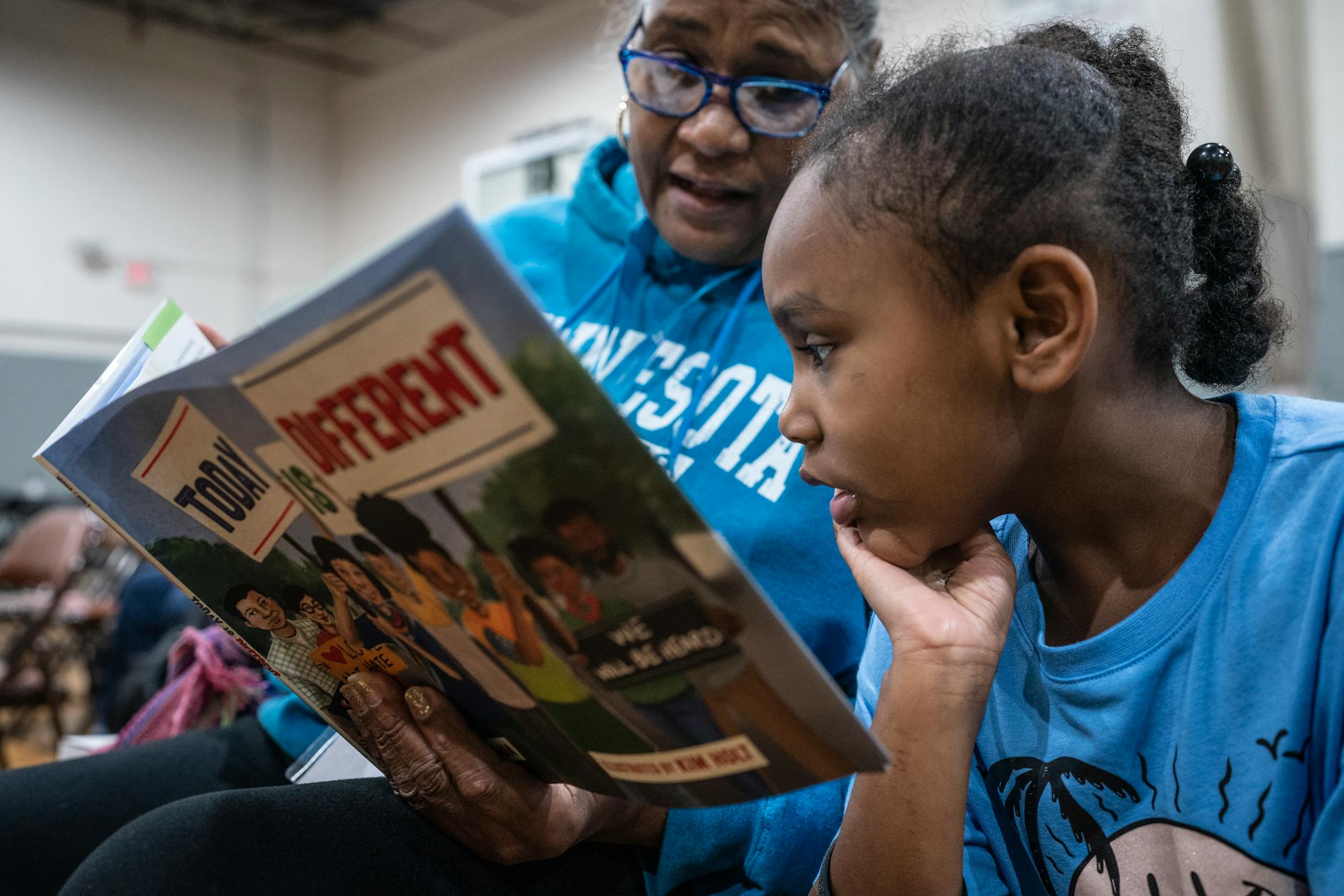 Rosa Rodriguez, left and her niece Summer 5, read a book together at the Dr. Martin Luther King Jr. celebration at Powerhorn Park.