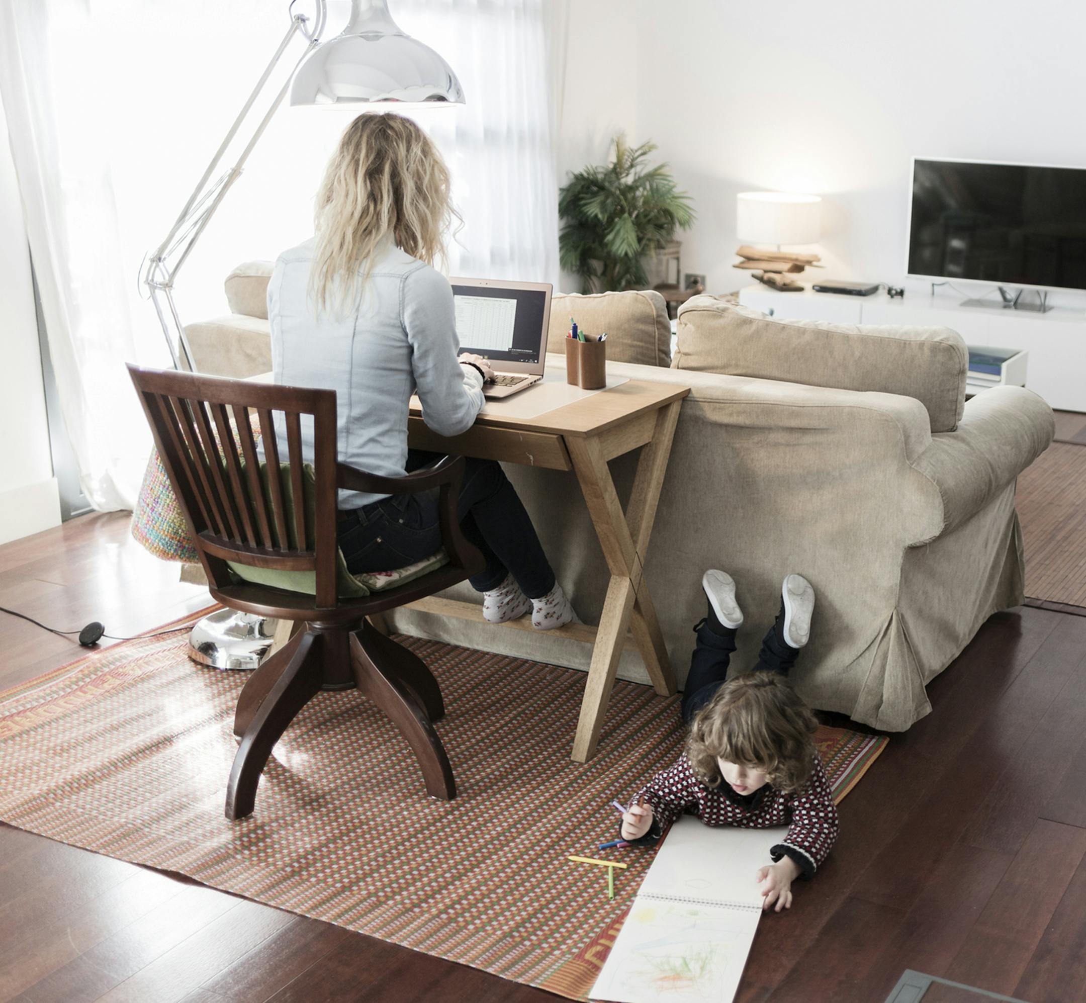 Mother working while child is drawing at home