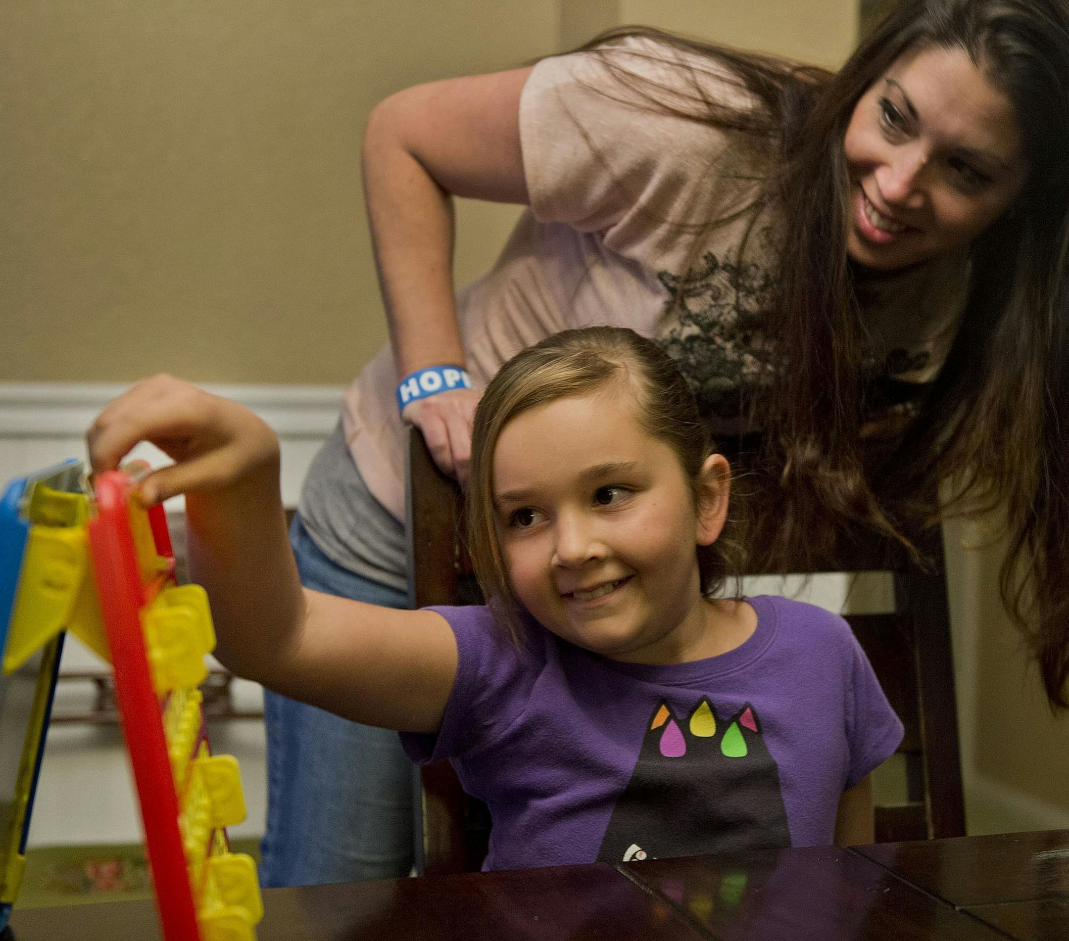 Evan Whisenant, 10, plays a game of Guess Who with help from her mom, Shannon, on Nov. 26, 2013. Evan beat leukemia five years ago but still suffers from side effects of the treatments.
