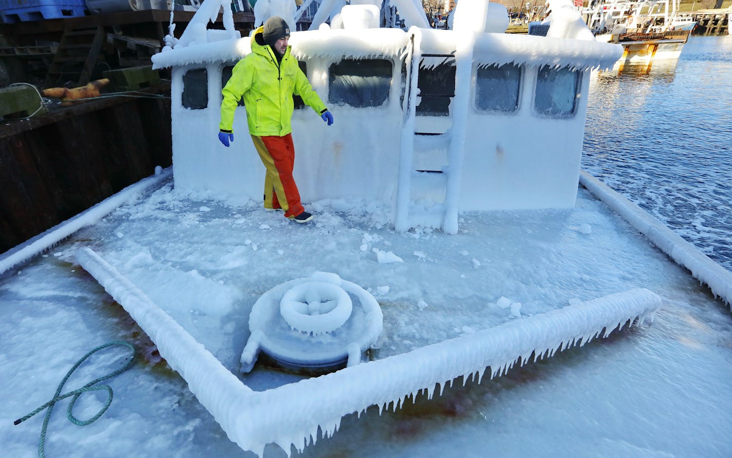 With temperatures in the single digits, Ray Levesque, mate of the crab/lobster boat Bradbill, makes his way across the deck covered in ice to tie off, after arriving in New Bedford, Mass., harbor on Thursday, Dec. 28, 2017, from a one day fishing voyage. Temperatures across Massachusetts are not expected to rise above freezing for days. (Peter Pereira/Standard Times via AP)