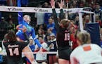 Eagan outside hitter Christine Jurgens (15) hit at the net as St. Louis Park's Raegan Alexander (14) and Makaila Winward (15) tried to block in the fi