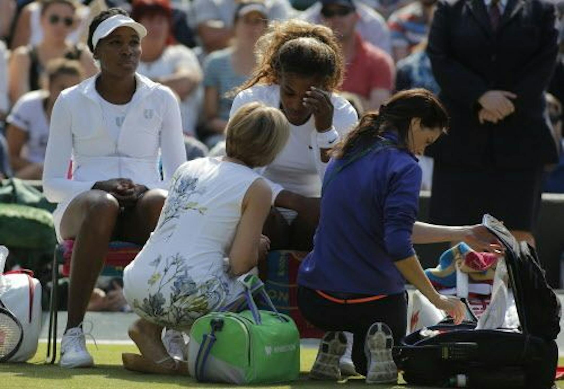 Court officials talk to Serena Williams and Venus Williams, left, of the U.S as they retire after 3 games from their women's doubles match against Kristina Barrois of Germany and Stefanie Voegele of Switzerland at the All England Lawn Tennis Championships in Wimbledon, London, Tuesday July 1, 2014.