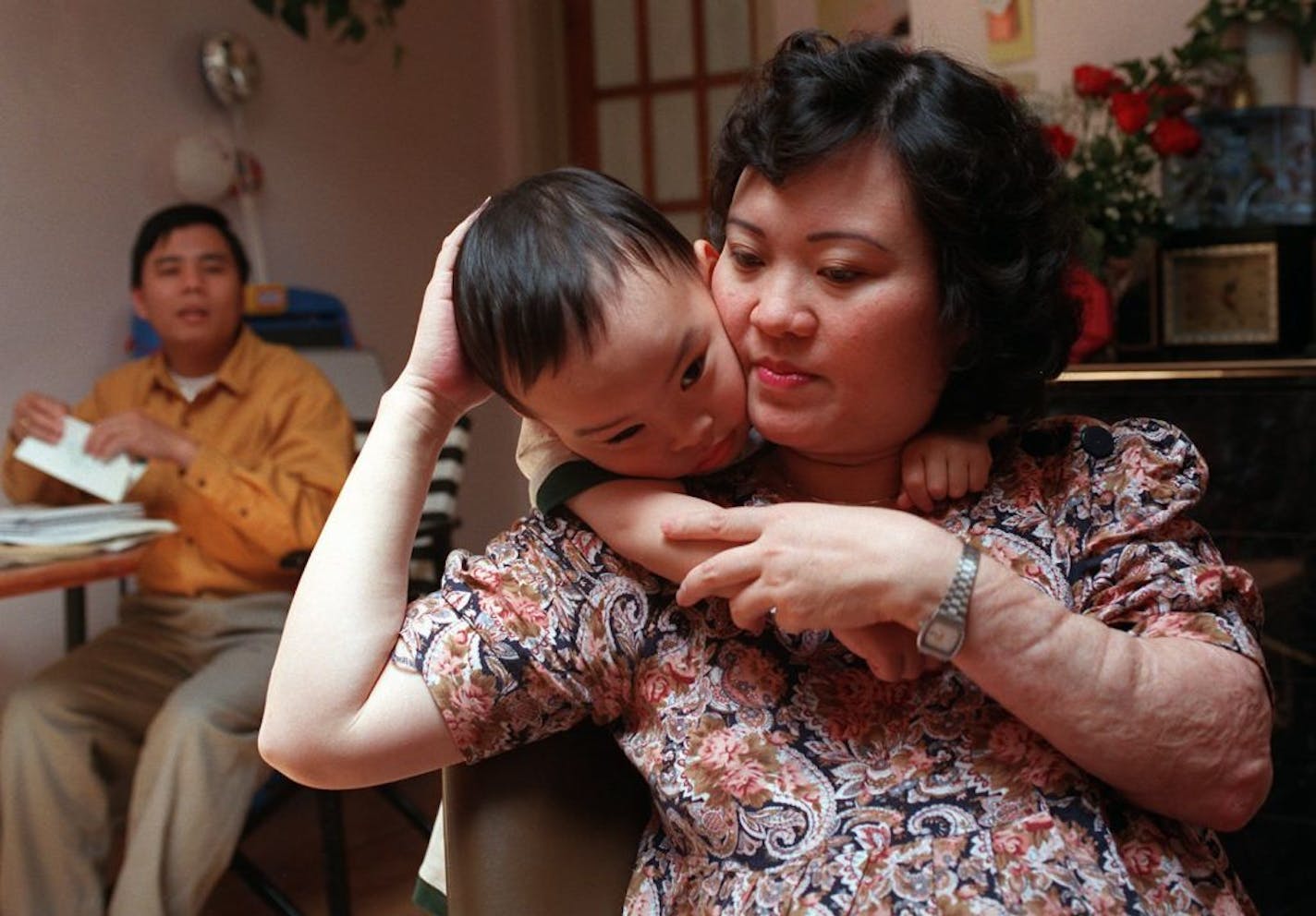 FILE - In this May 25, 1997 file photo, Phan Thi Kim Phuc holds her son Thomas, 3, in their apartment in Toronto. Her husband, Bui Huy Toan is at left. Kim Phuc's left arm shows evidence of the burns she suffered on June 8, 1972, when her village in Vietnam was hit by napalm bombs dropped by South Vietnamese warplanes acting on U.S. orders.