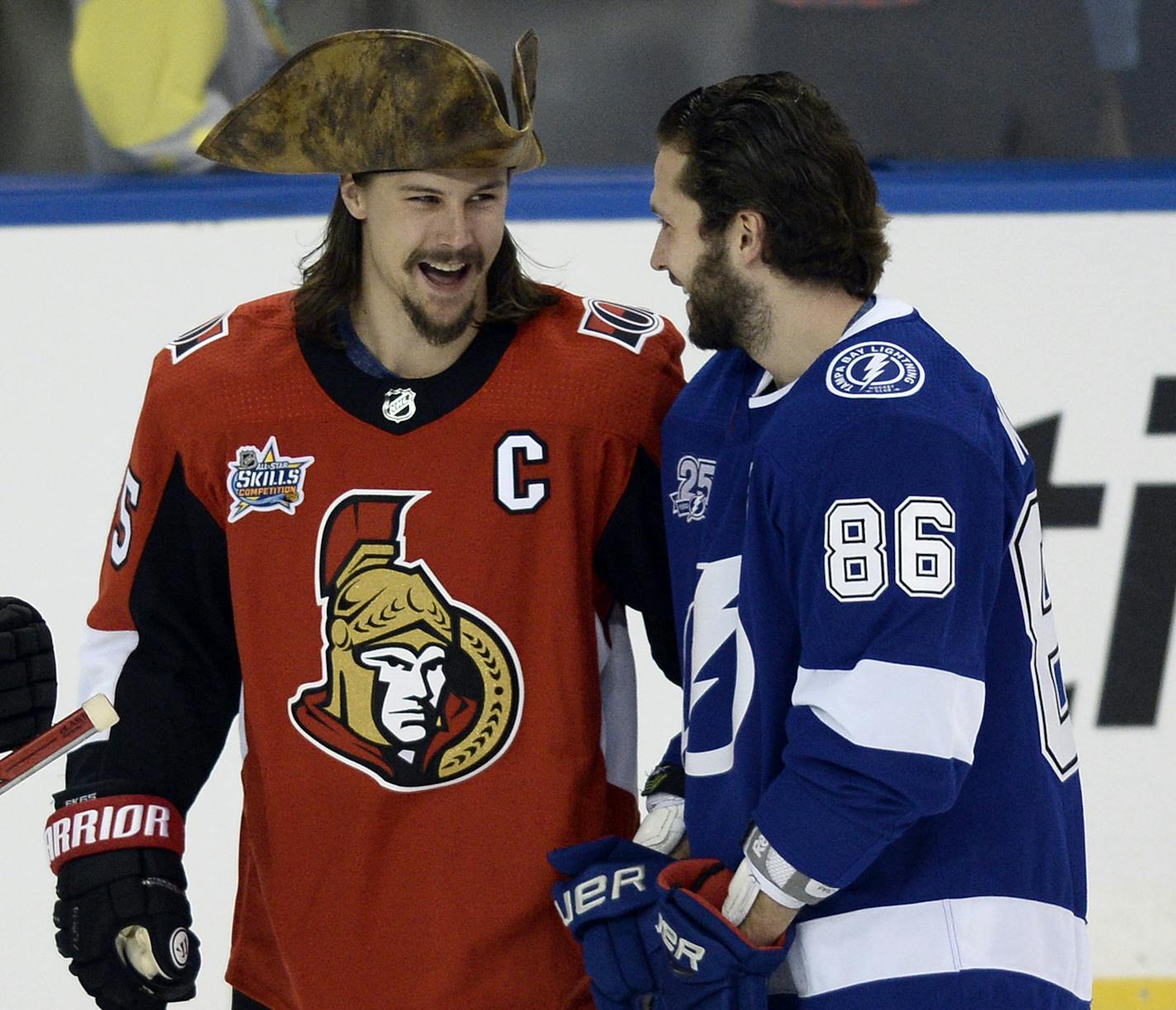 Ottawa Senators defenseman Erik Karlsson (65), wearing a pirate's hat, chats with Tampa Bay Lightning's Nikita Kucherov (86) before the Skills Competition, part of the NHL All-Star Game events, Saturday, Jan. 27, 2018, in Tampa, Fla. (AP Photo/Jason Behnken) ORG XMIT: TPA121