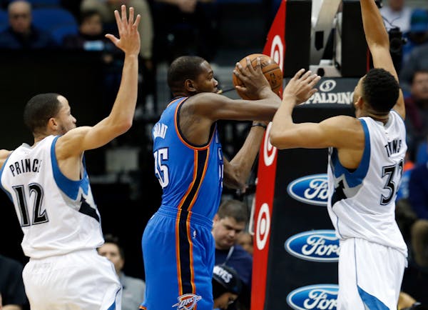 Oklahoma City's Kevin Durant looked to pass between the Timberwolves' Tayshaun Prince, left, and Karl-Anthony Towns in the first quarter during a game