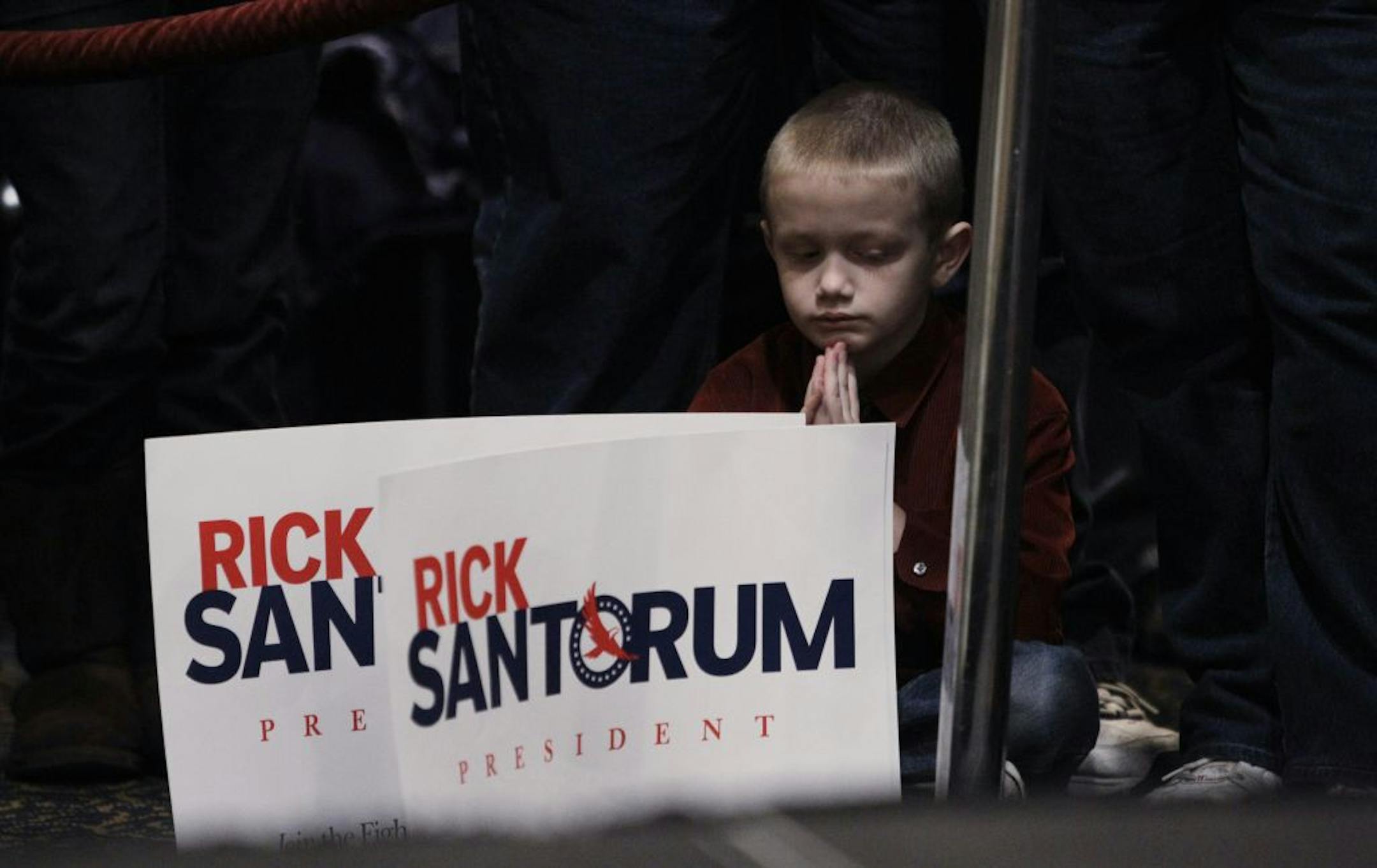 A young boy listens to Republican presidential candidate, former Pennsylvania Sen. Rick Santorum, speaking at a Tea Party rally, Saturday, Feb. 25, 2012, in St. Clair Shores, Mich.