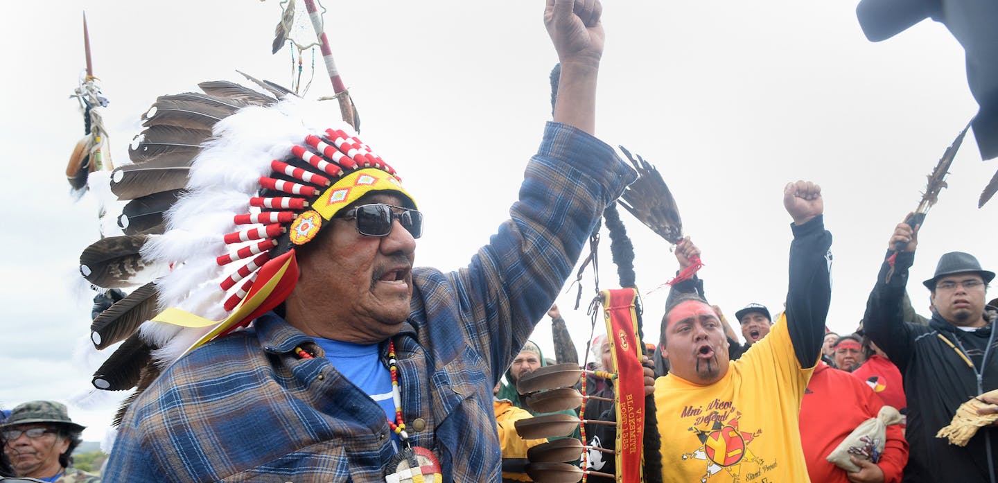 JR American Horse, left, raises his fist with others while leading a march to the Dakota Access Pipeline site in southern Morton County North Dakota. Several hundred protesters marched about a mile up Hwy 1806, Friday Sept. 9, 2016, from the protest camp to the area of the pipeline site where some archeological artifacts have been discovered. (Will Kincaid/The Bismarck Tribune via AP) ORG XMIT: MIN2016090918491340