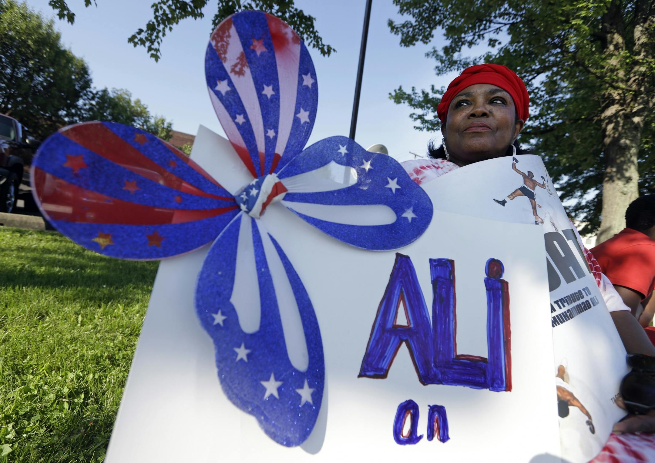Frances Woods holds a sign saluting Muhammad Ali as she awaits his funeral procession to make its way down Muhammad Ali Boulevard in Louisville, Ky. Friday, June 10, 2016.