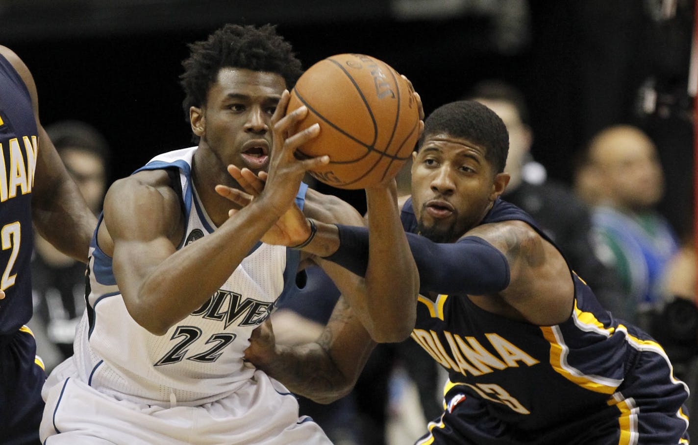 Minnesota Timberwolves guard Andrew Wiggins (22) looks to pass to a teammate under pressure from Indiana Pacers forward Paul George, right, during the first half of an NBA basketball game in Minneapolis, Saturday, Dec. 26, 2015.