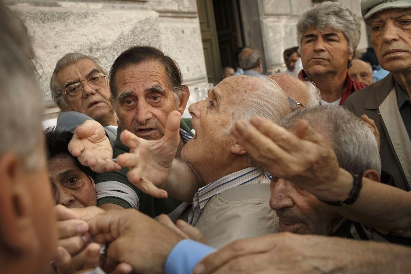 Pensioners try to get a number to enter inside a bank in Athens, Wednesday, July 1, 2015. About 1,000 bank branches around the country were ordered by the government to reopen Wednesday to help desperate pensioners without ATM cards cash up to 120 euros ($134) from their retirement checks. Eurozone finance ministers were set to weigh Greece's latest proposal for aid Wednesday.