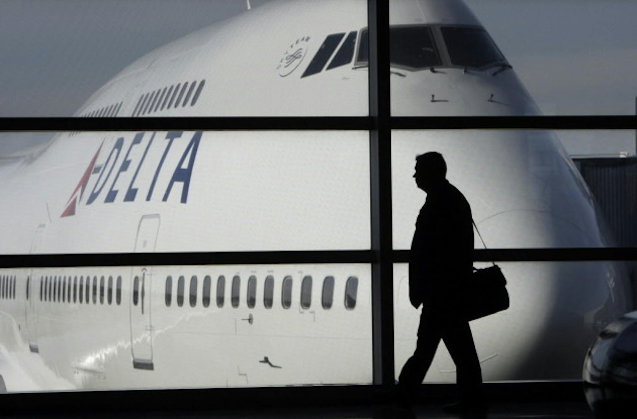 In this Jan. 21, 2010 file photo, a passenger walks past a Delta Airlines 747 aircraft in McNamara Terminal at Detroit Metropolitan Wayne County Airport in Romulus, Mich. (AP Photo/Paul Sancya, file)