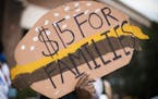 A man holds a sign shaped like a cheeseburger during a rally and march supporting $15 minimum wage on W. Broadway Avenue. ] (Leila Navidi/Star Tribune