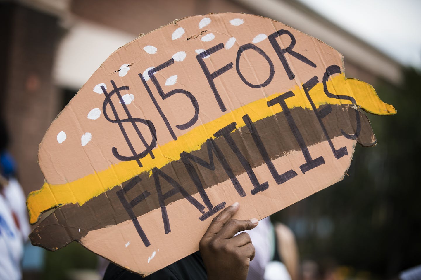 A man holds a sign shaped like a cheeseburger during a rally and march supporting $15 minimum wage on W. Broadway Avenue. ] (Leila Navidi/Star Tribune) leila.navidi@startribune.com BACKGROUND INFORMATION: Activists supporting a $15 minimum wage rally and march outside corporate fast food restaurants, payday lenders and a bank on W. Broadway Avenue in north Minneapolis on Monday, September 12, 2016. The activists are pushing for an ordinance passage at City Hall this year for a $15 minimum wage i