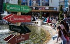 A directional sign is seen as shoppers sit around a fountain at The Grove in Los Angeles, on Dec. 22, 2017.