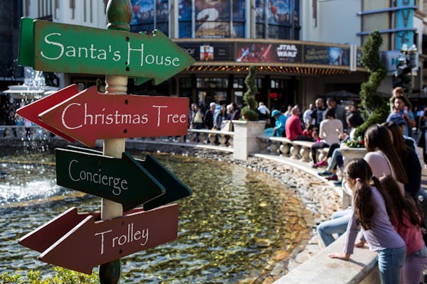 A directional sign is seen as shoppers sit around a fountain at The Grove in Los Angeles, on Dec. 22, 2017.