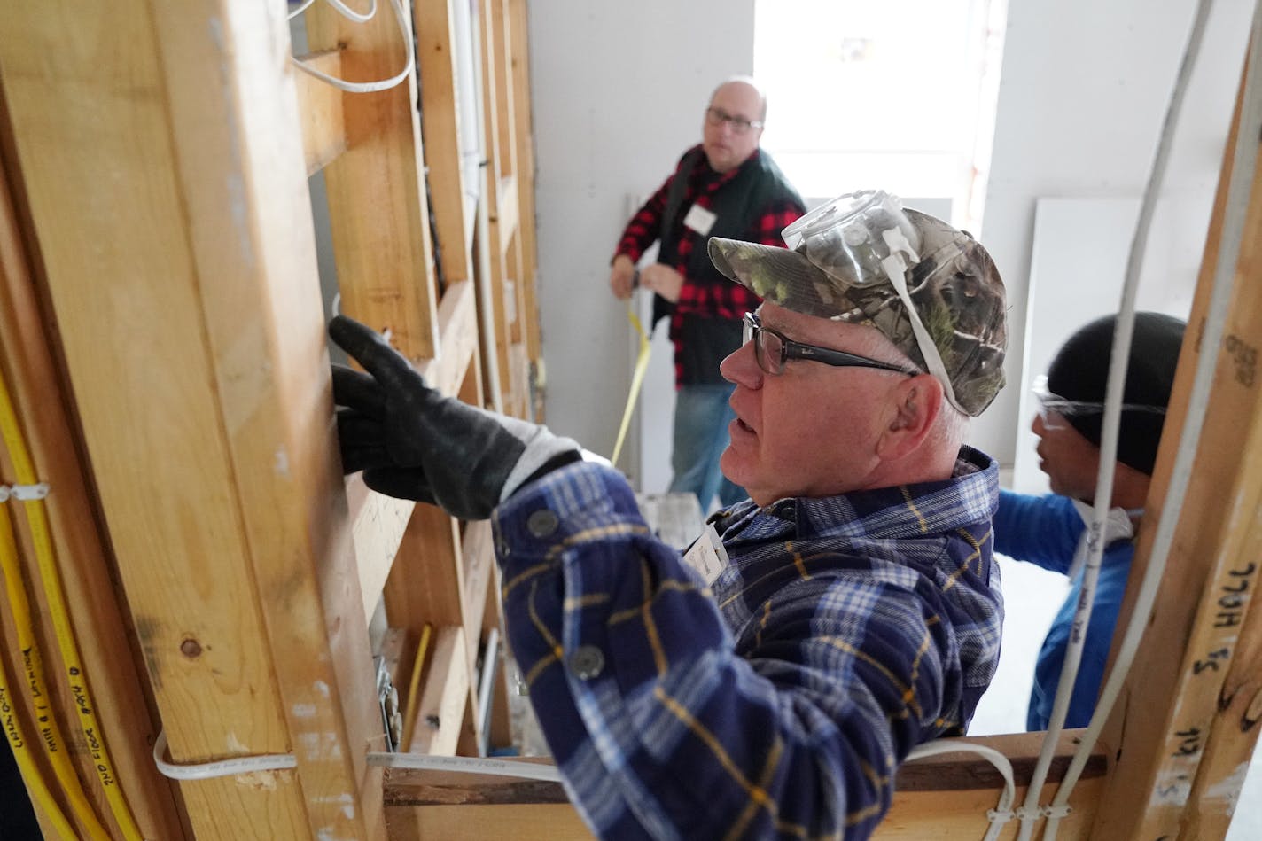 Gov. Tim Walz worked Tuesday with Twin Cities Habitat for Humanity site supervisor Jesse Dinh, right, and fellow volunteer, Deluxe Corp. CEO Barry McCarthy, to install drywall in a home at the Willow Reserve site in St. Paul. (ANTHONY SOUFFLE/Star Tribune)